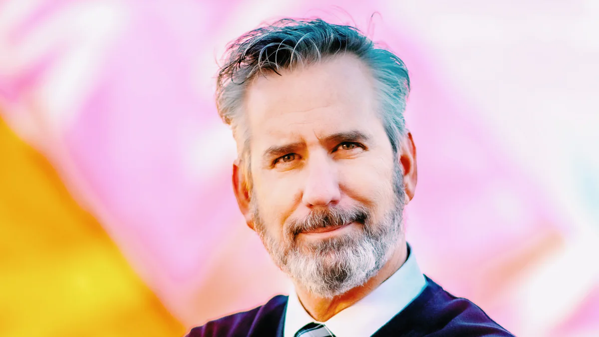 Kendall Smith, Director of Programming at TACAW in Basalt, in a navy suit against a colorful backdrop