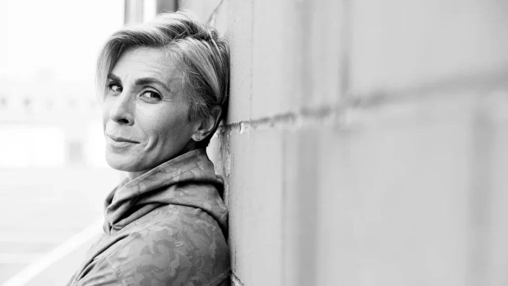 Danielle Pellicano, Aspen endurance coach, leaning against a white wall, black and white portrait
